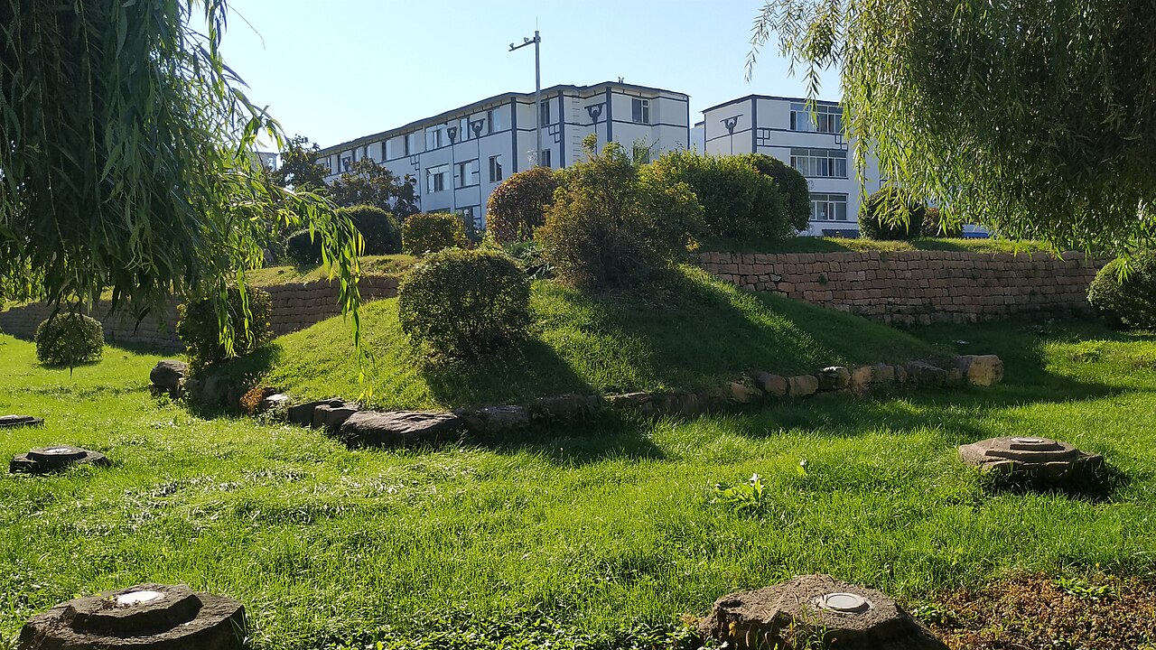 Low stone remains at Guonei’s southeast corner, with modern Ji’an buildings beyond
