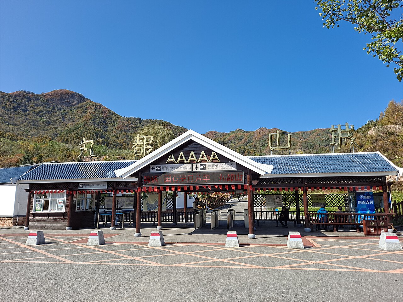 Modern Wandu Mountain City visitor entrance with the Chinese site name and hills behind
