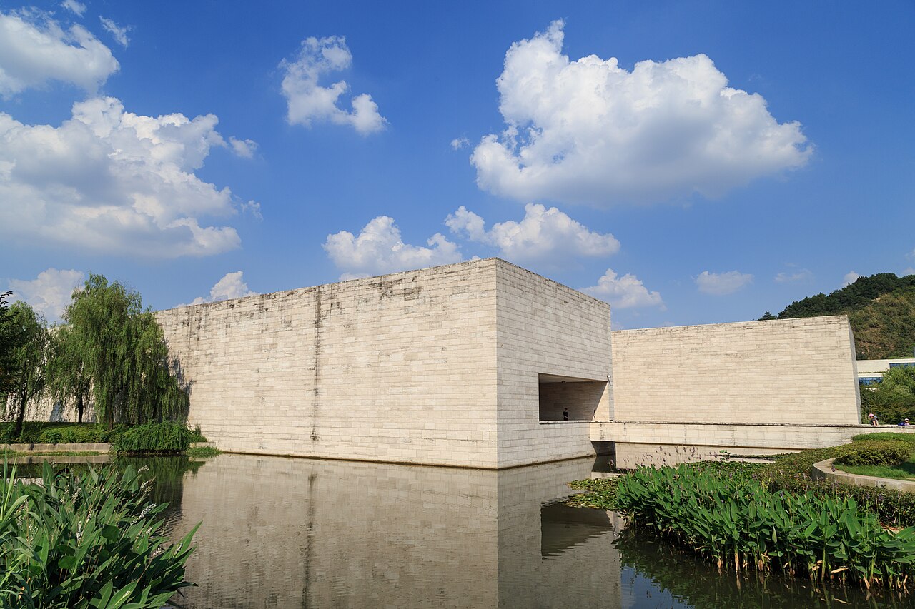 Stone-clad Liangzhu Museum building beside its water and planting