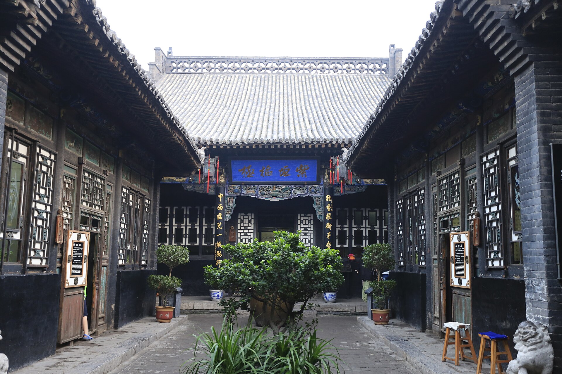 Rishengchang courtyard showing aligned doorways, timber screens and interpretation panels