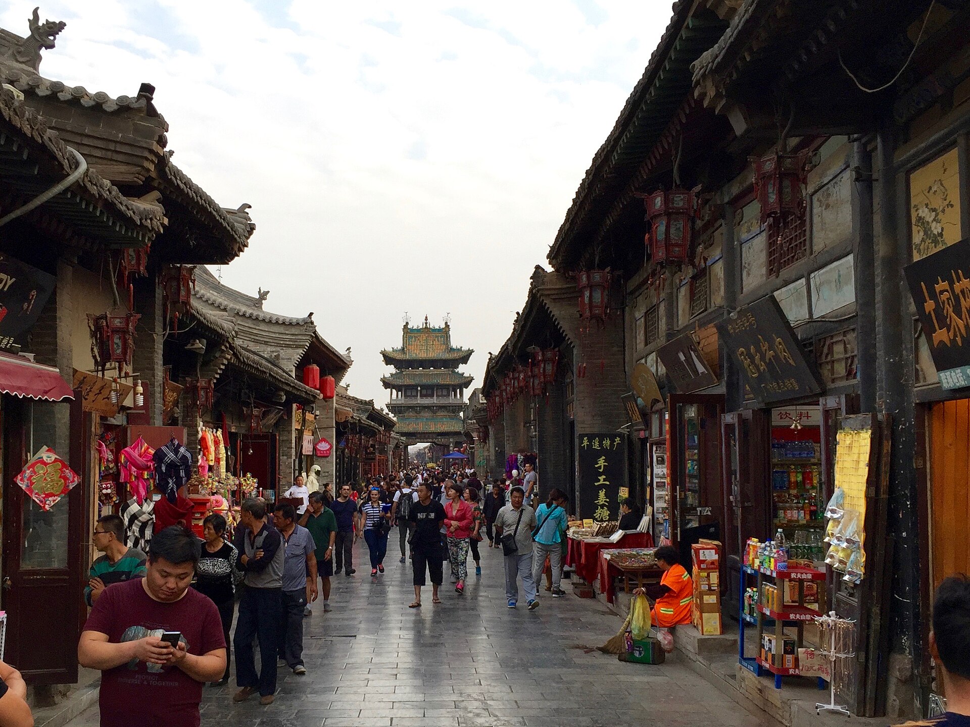 Visitors and historic shopfronts on Pingyao South Street with the City Tower beyond