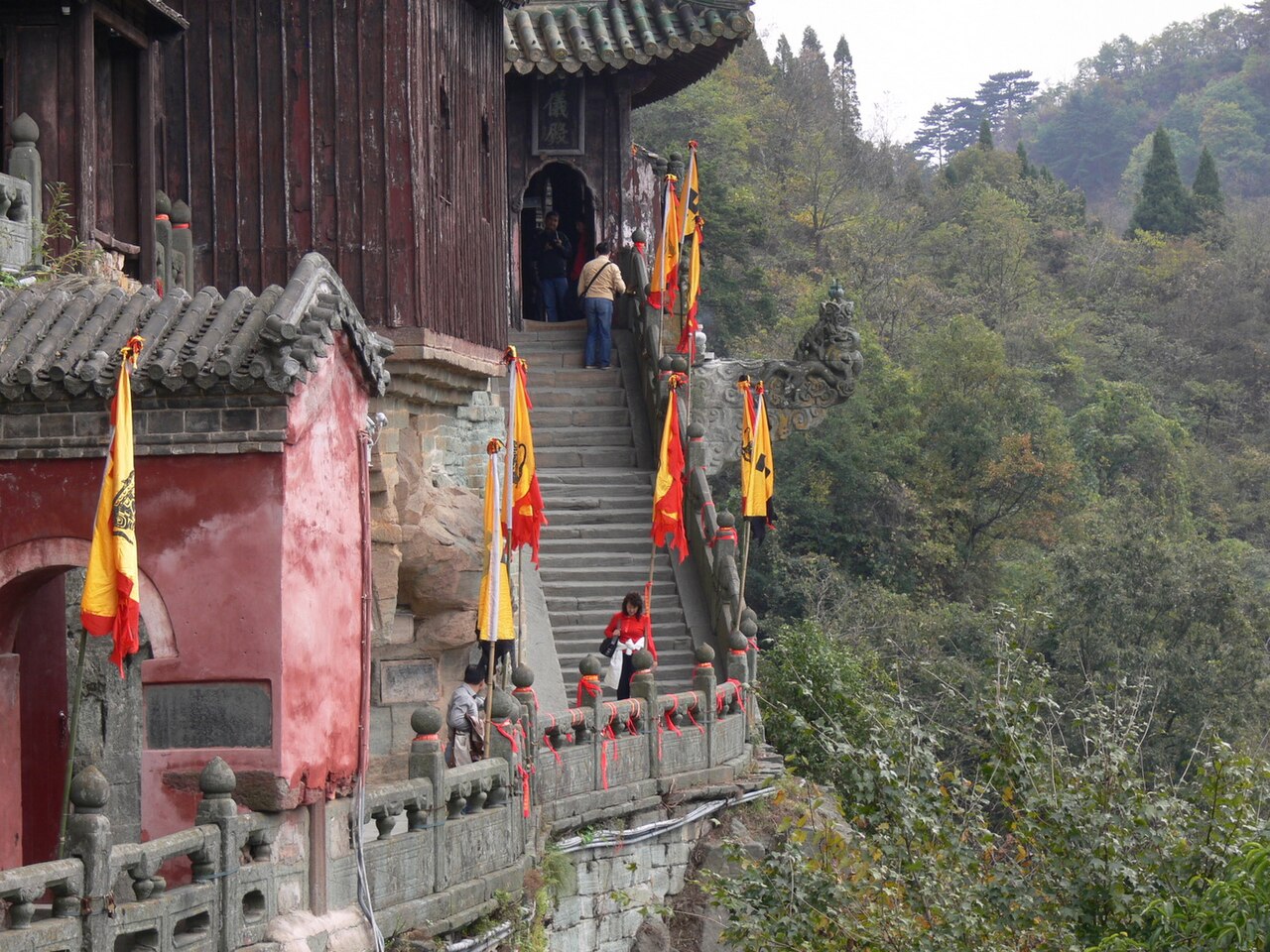 Stone steps beside the Two Principles Hall at Nanyan Palace, with forested slope beyond